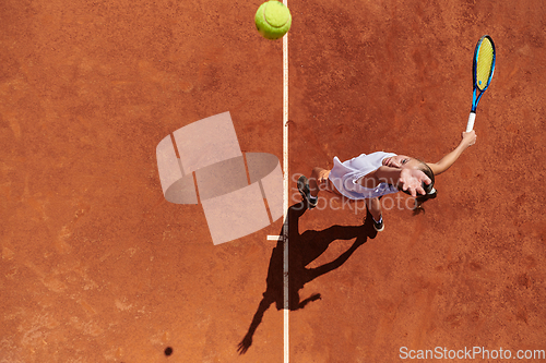 Image of Top view of a professional female tennis player serves the tennis ball on the court with precision and power