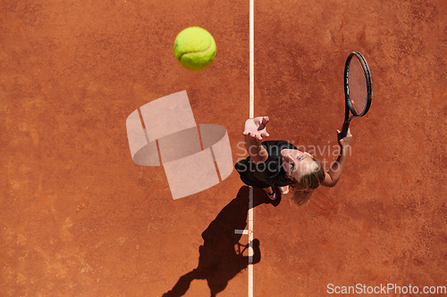 Image of Top view of a professional female tennis player serves the tennis ball on the court with precision and power