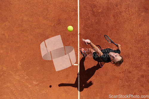 Image of Top view of a professional female tennis player serves the tennis ball on the court with precision and power