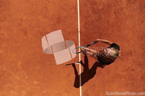 Image of Top view of a professional female tennis player serves the tennis ball on the court with precision and power