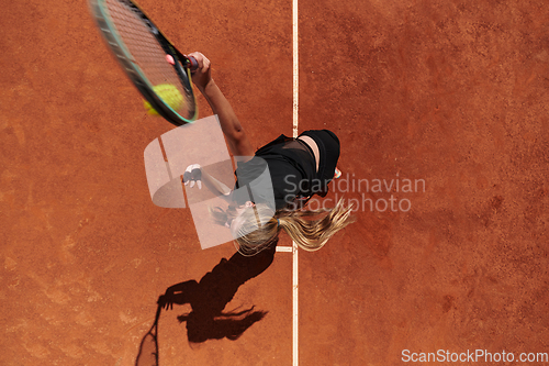 Image of Top view of a professional female tennis player serves the tennis ball on the court with precision and power