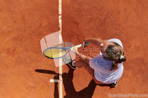 Image of Top view of a professional female tennis player serves the tennis ball on the court with precision and power