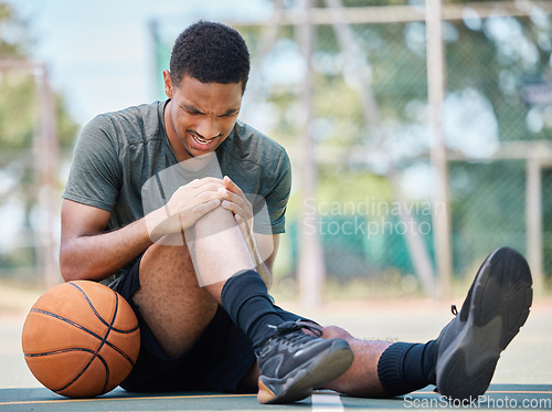 Image of Basketball court, man and injury, knee pain and joint pain, fitness emergency and first aid accident, risk and bone health. Black man, basketball player and leg pain, muscle inflammation and problem