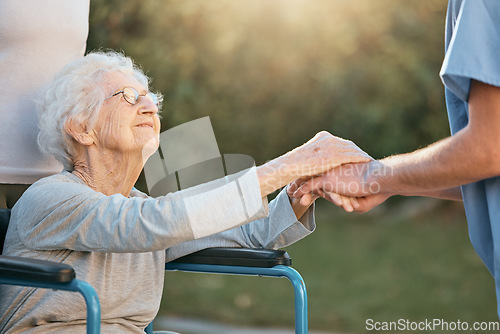 Image of Elderly woman, wheelchair and caregiver holding hands for support, care and solidarity in nature park. Senior person, patient disability and healthcare nurse communication in retirement home outdoor