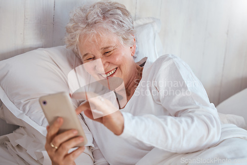 Image of Happy elderly woman, bed or phone on social media for meme, comic or joke on internet. Senior lady, bedroom or smartphone tech with laugh at social network, funny video or email on web, app or online