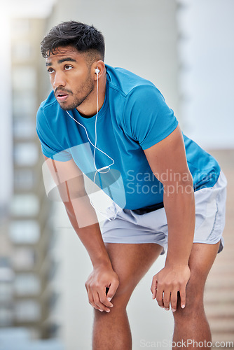 Image of Tired, fitness and sweat with earphones music for cardio, workout and athletic training break. Exercise, exhausted and sweaty indian man listening to audio streaming on outdoor athlete rest.