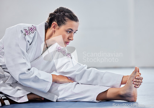 Image of Martial arts, fitness and stretching with woman in karate school for training, sports and fight performance. Strong, focus and warm up with girl student in dojo studio for taekwondo, workout or club