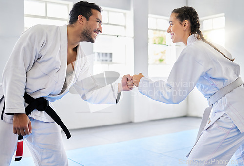 Image of Karate, motivation and fist bump with a man and woman fighter training together in a gym or dojo. Fitness, exercise and fight with a male and female athlete in a health club for combat sports