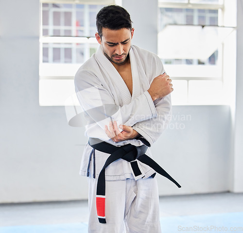 Image of Karate, arm pain and man with injury in dojo, healthcare and fighting. Sports, fitness and martial arts fighter in India with hand elbow sports injury and medical emergency in fighting gym or studio.