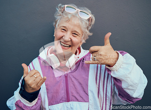 Image of Shaka sign, portrait and senior woman in retirement standing by gray wall with a smile or happiness. Happy, fun and friendly elderly lady pensioner in the outdoor city with a hang loose hand gesture.