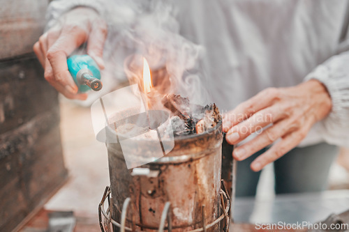 Image of Fire, camping and hands of a senior person start a flame for heating, preparation of food and cooking in nature. Light, heat and woman with a tool for making heat and warmth during an outdoor camp