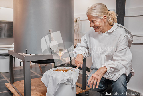 Image of Happy, smile and beekeeper working with honey for eco friendly, organic and natural production at warehouse. Business owner with happiness for the process of sweet food from a machine in agriculture