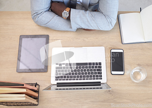 Image of Laptop, tablet and phone with a business man sitting at his desk in the office at work from above. Flatlay, computer and technology with a male employee working on a table or wooden surface