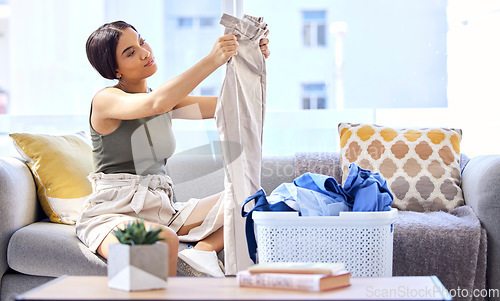 Image of Laundry, housekeeping and woman folding clothes, cleaning and working in the living room of her house. Routine, washing and cleaner with clean clothing in a basket on the sofa of the home lounge