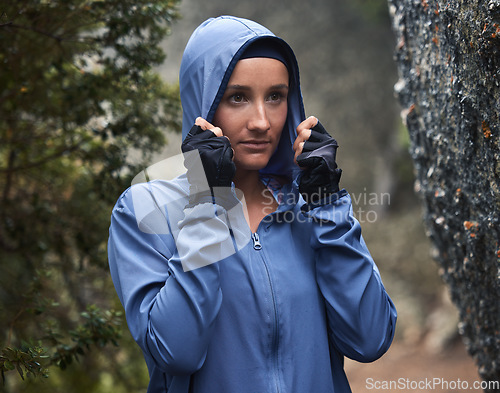 Image of Woman, hiking and forest with rain on adventure, travel and explore nature on winter vacation. Girl, hiker and hoodie for safety in woods, cold or weather by trees, hiking trail or walk for fitness
