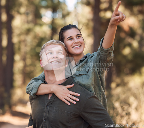 Image of Couple piggy back, happy and hiking in nature, relax or smile, hand and pointing while trekking in nature. Friends, hikers and woman with man in forest, exercise, cardio or adventure outdoor together