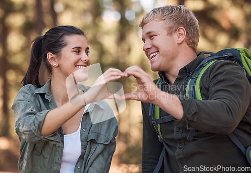 Image of Love, couple and heart hands while hiking in nature for affection or support. Emoji, hand gesture and romance or intimacy shape with happy man and woman on adventure or trekking outdoors in forest.