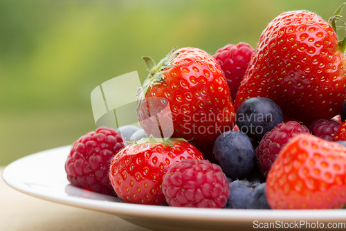 Image of Pile od strawberries, blueberries, raspberries on green background