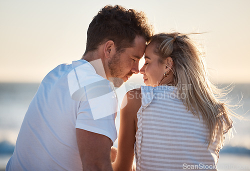 Image of Love, beach and couple with head together enjoying romantic holiday, honeymoon and vacation together. Summer, travel and man and woman sitting by ocean bonding, faces touching and show affection