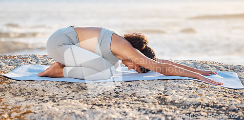 Image of Beach yoga, fitness and woman stretching down, kneeling and balance, childs pose and health. Balasana exercise, mindfulness and sea workout, energy and wellness, zen and pilates, nature or meditation