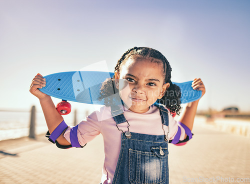 Image of Skateboard, portrait and girl child at the beach promenade for skating practice on an outdoor promenade. Sports, training and kid with comic face while skateboarding by the ocean on seashore vacation