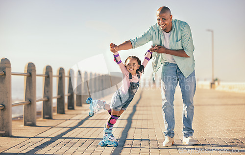 Image of Skating, learning and father holding hands of his child while teaching her on the beach promenade. Family, love and dad helping his young girl kid for support, balance and care to outdoor rollerskate