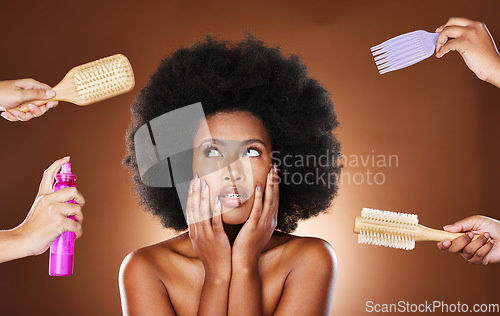 Image of Haircare, hairspray and brush with a model black woman in studio with a choice of care for afro hair in hands. Beauty, cosmetics and backstage with an attractive young female on a brown background