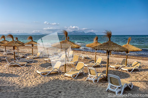 Image of Can Picafort Beach with straw umbrellas and sun loungers, Can Picafort, Balearic Islands Mallorca Spain.