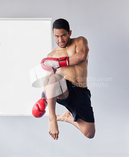 Image of Muay thai, jump and fitness with man kick boxing for training, martial arts and and sports fight. Action, workout and energy with athlete and boxing gloves for mma, champion and exercise in dojo gym