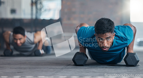 Image of Fitness, dumbbell weights and men doing a push up exercise for strength, health and wellness in a gym. Sports, motivation and athletes doing a workout or training routine together in a sport center.