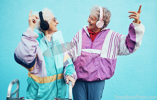 Image of Friends, city and senior women with headphones on blue background wall listening to audio, music and radio. Fashion, style and elderly females enjoy retirement, freedom and dancing in urban town