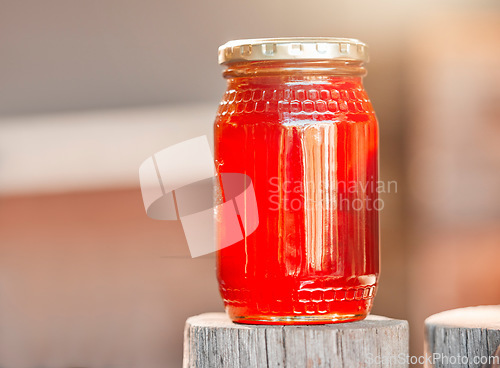 Image of Honey, jar and background of glass, healthy nutrition and sugar production from bee farming, organic and sustainability from nature. Closeup bottle, liquid and honeycomb container, package and syrup