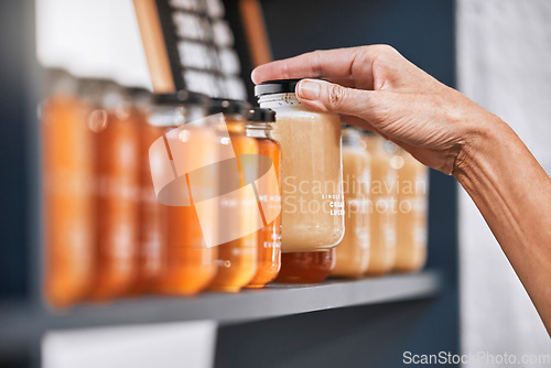 Image of Hands, jar and honey shelf for inventory check, product pricing or labeling in organic retail store. Hand in small business, management or market advertising of healthy glass food products for sale