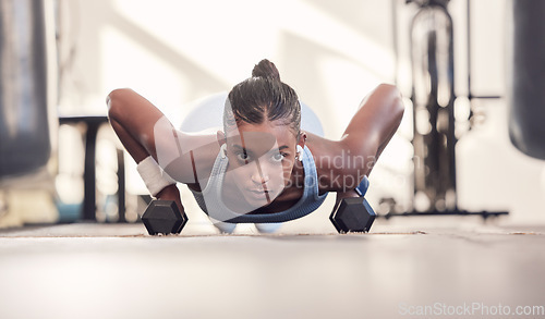 Image of Dumbbell, fitness and black woman training, workout or bodybuilder in gym floor portrait for body goals, muscle and wellness motivation. Strong, power and sports girl doing push up exercise with gear