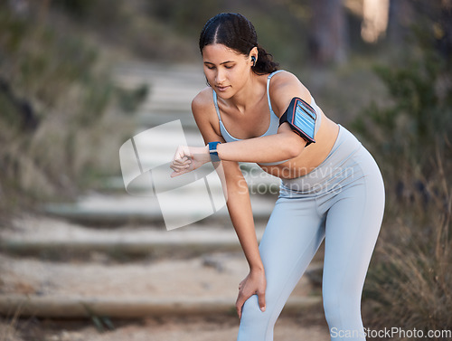 Image of Fitness, running and woman with a smartwatch doing a cardio workout in the woods for health. Sports, wellness and athlete training for a race, marathon or exercise in nature in a forest with a watch.