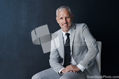 Image of Studio portrait, happy businessman and chair in mockup space with confident boss on dark background. Smile, pride and professional career for executive, mature startup business owner or startup ceo.