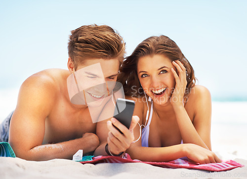 Image of Happy, music and a couple at the beach with a phone for a podcast, radio or social media in Mexico. Smile, relax and a man and woman with mobile app for audio during a holiday by the ocean in summer