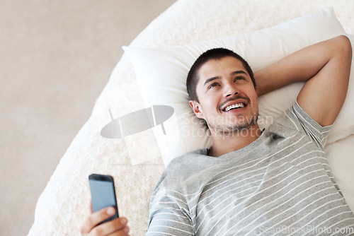 Image of Man, happy and thinking with a phone on a bed for communication, chat or notification at home. Happy young person with a smartphone for message idea with internet connection, app and social media