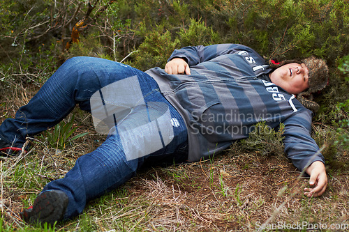 Image of Drunk, sleeping and hangover with a plus size man lying outdoor on the grass or ground after a party. Festival, alcohol and tired with a young male person asleep on a field or lawn in the morning