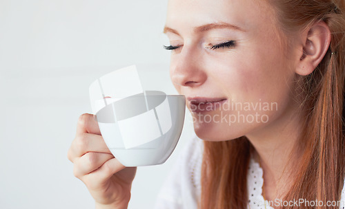 Image of Face of woman smell her cup of coffee in a studio for a scent in the morning on a weekend. Calm, relax and female model enjoying the aroma of a cappuccino, caffeine or latte by a white background.