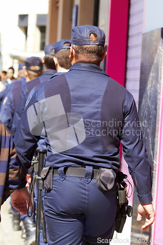 Image of Police, group and walking in city for safety, law enforcement and urban patrol from the back. Security, team of people and public service cops with legal power, authority and crime guard in street