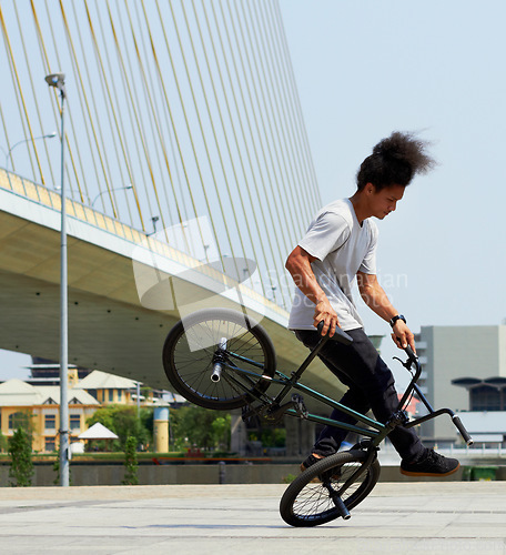 Image of Boy, action and city with bicycle with trick or training with concrete for transportation. Cycling, outdoor and bmx with male hipster for fun and hobby with bridge and action for balance with stunt.