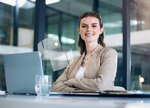 Image of Business woman, arms crossed and working at desk with laptop, lawyer with confidence and smile in portrait. Professional mindset, female employee at law firm with mission, attorney and legal research