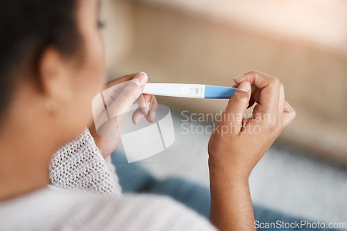 Image of Pregnancy test, woman hands and waiting at home for results on a living room couch. House, female person and hand with testing stick to show pregnant sign while checking alone on lounge sofa