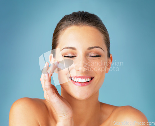 Image of Skincare, smile and woman with cream on face, cosmetics and makeup product on blue background. Happiness, skin care and wellness for happy model with beauty, lotion and dermatology for facial glow.