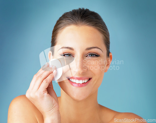 Image of Dermatology, portrait and happy woman with cotton pad on face, skincare and makeup cleaning product. Cosmetics, skin care and wellness for model with beauty, detox and facial glow on blue background.