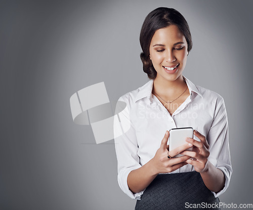 Image of Phone, communication and corporate with a business woman in studio networking on a gray background. Mobile, contact and smile with a happy female professional or employee typing a text message