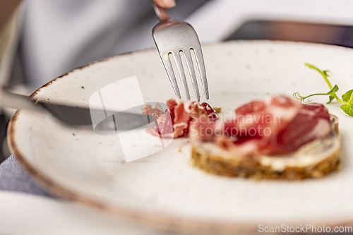 Image of Person eating bruschetta with prosciutto