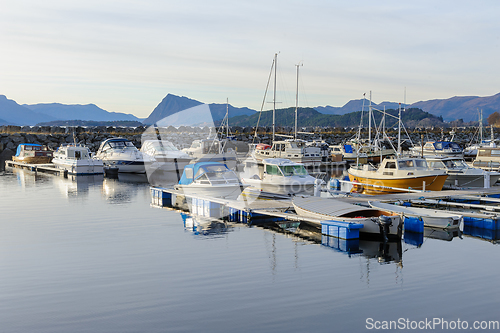 Image of boats within breakwater reflecting in blue the sea