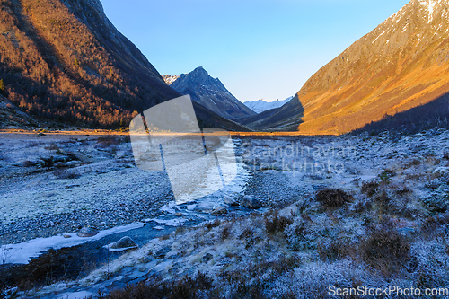 Image of frozen landscape in the foreground with ice in a river flowing t